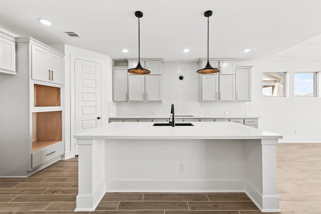 kitchen with dark hardwood / wood-style flooring, sink, and a kitchen island with sink