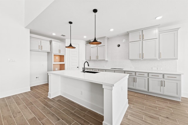 kitchen featuring hardwood / wood-style floors, a kitchen island with sink, pendant lighting, and sink