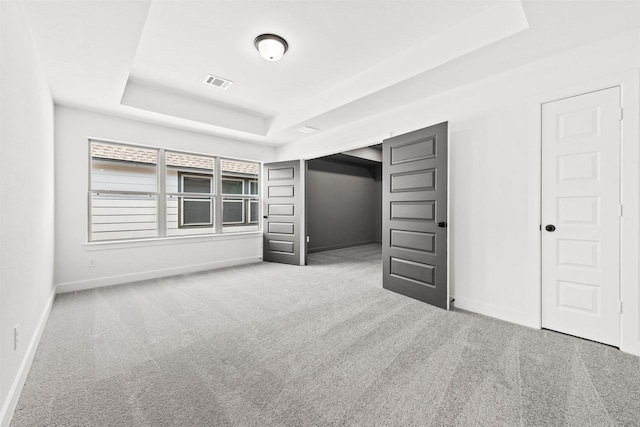 unfurnished bedroom featuring carpet floors and a tray ceiling