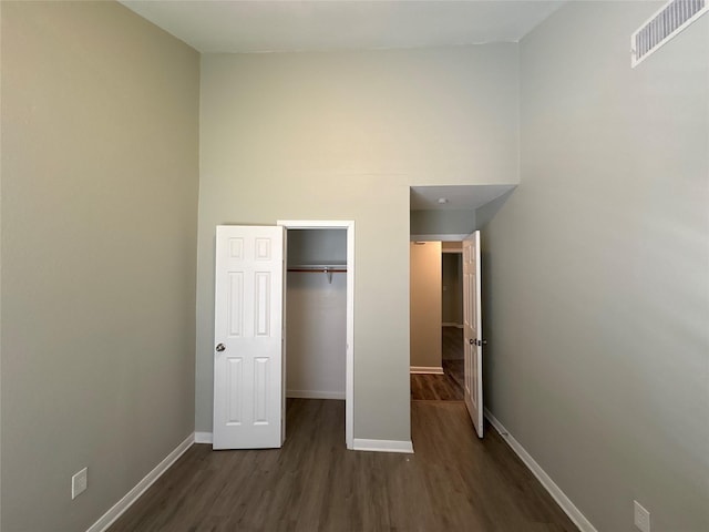 unfurnished bedroom featuring a walk in closet, a closet, and dark wood-type flooring