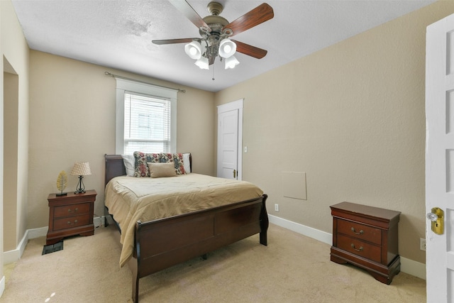 bedroom with ceiling fan, light colored carpet, and a textured ceiling