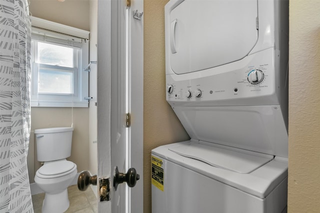 clothes washing area featuring light tile patterned floors and stacked washer / drying machine