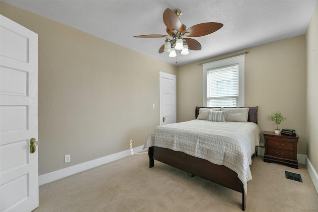 bedroom featuring a textured ceiling, light colored carpet, and ceiling fan