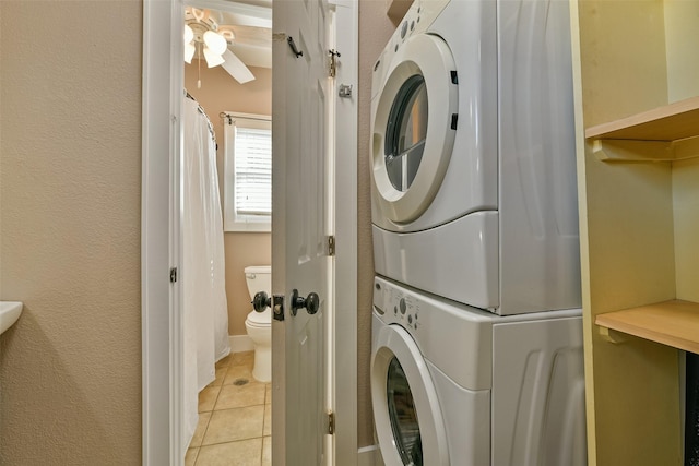 clothes washing area featuring light tile patterned floors, stacked washer and dryer, and ceiling fan