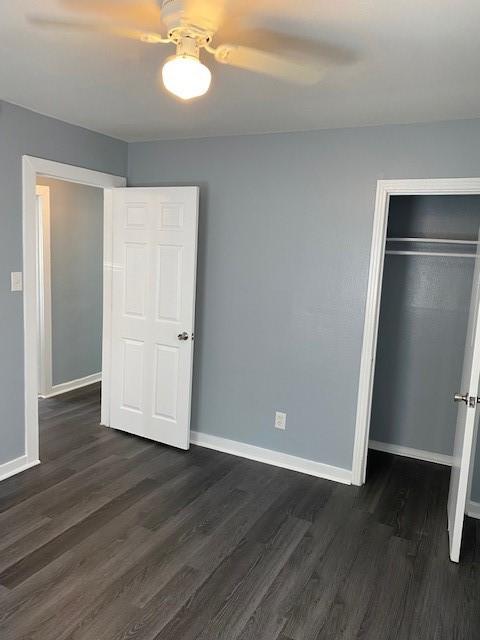 unfurnished bedroom with ceiling fan, dark hardwood / wood-style flooring, and a closet