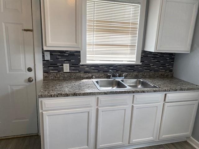 kitchen with decorative backsplash, white cabinetry, and sink