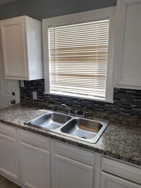 kitchen featuring white cabinets, tasteful backsplash, and sink