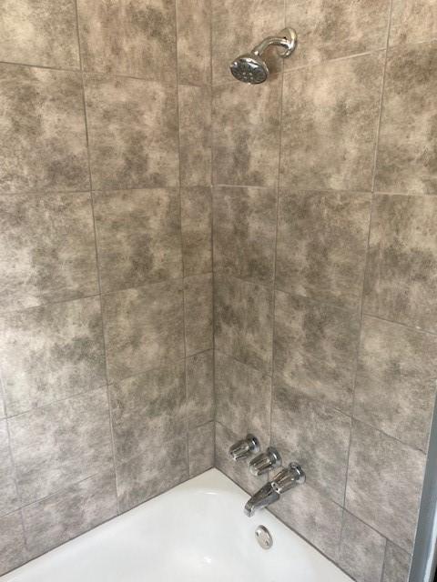 interior details featuring tiled shower / bath combo