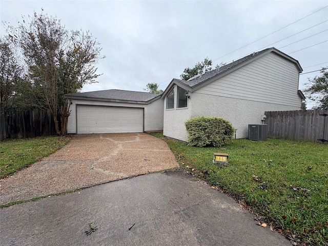 ranch-style home with central AC unit, a front yard, and a garage