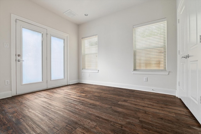 empty room with dark hardwood / wood-style floors and a healthy amount of sunlight