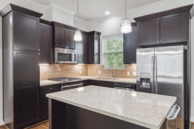 kitchen with pendant lighting, sink, hardwood / wood-style flooring, a kitchen island, and stainless steel appliances