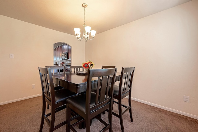 dining space with carpet and a notable chandelier