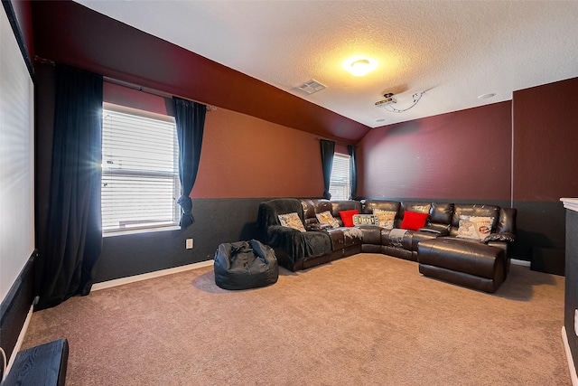 carpeted home theater room featuring vaulted ceiling and a textured ceiling