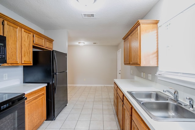 kitchen featuring light tile patterned floors, a textured ceiling, black appliances, and sink