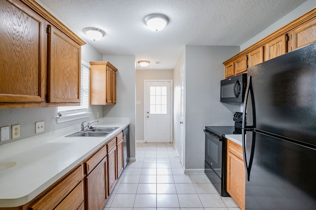 kitchen featuring sink, light tile patterned floors, black appliances, and a textured ceiling