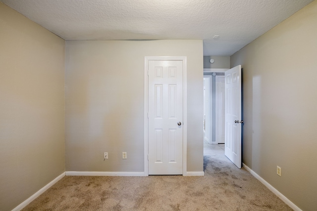 unfurnished bedroom with light colored carpet and a textured ceiling