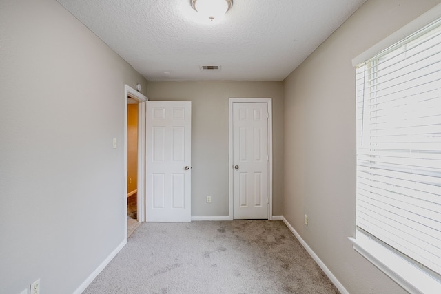 unfurnished bedroom featuring light carpet, a textured ceiling, and a closet