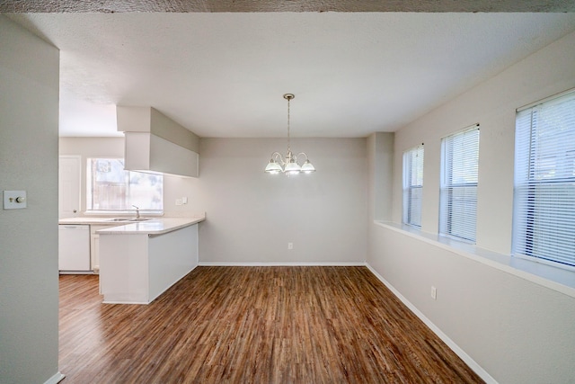 kitchen with dishwasher, sink, an inviting chandelier, dark hardwood / wood-style floors, and white cabinets