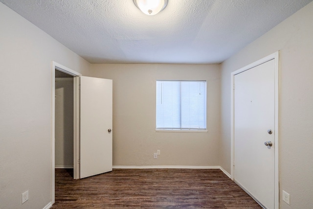 unfurnished bedroom featuring a textured ceiling and dark wood-type flooring