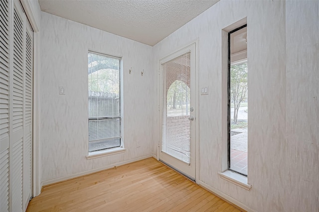 doorway to outside featuring a textured ceiling and light hardwood / wood-style flooring