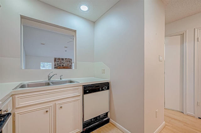 kitchen with a textured ceiling, white dishwasher, light hardwood / wood-style floors, and sink