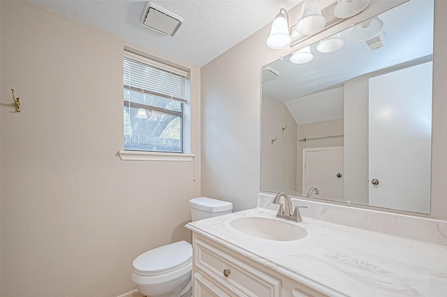 bathroom with vanity, toilet, and a textured ceiling