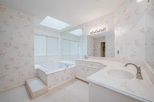 bathroom featuring tiled bath, vanity, a textured ceiling, and a skylight