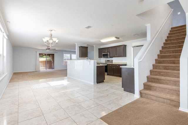 kitchen featuring appliances with stainless steel finishes, dark brown cabinets, a center island with sink, a notable chandelier, and hanging light fixtures