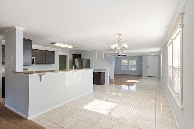 kitchen with kitchen peninsula, appliances with stainless steel finishes, a breakfast bar, dark brown cabinets, and a chandelier