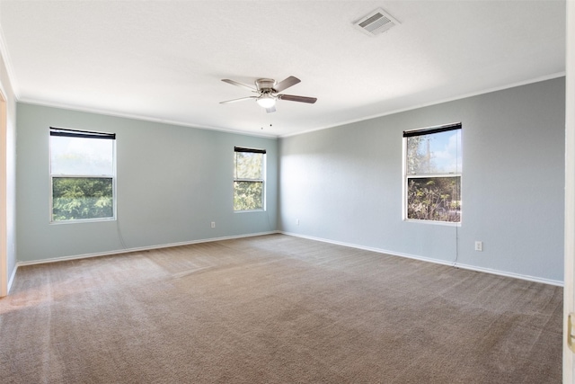 carpeted spare room featuring a wealth of natural light, crown molding, and ceiling fan