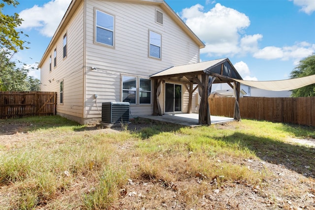 rear view of property featuring a yard, central AC, and a patio area