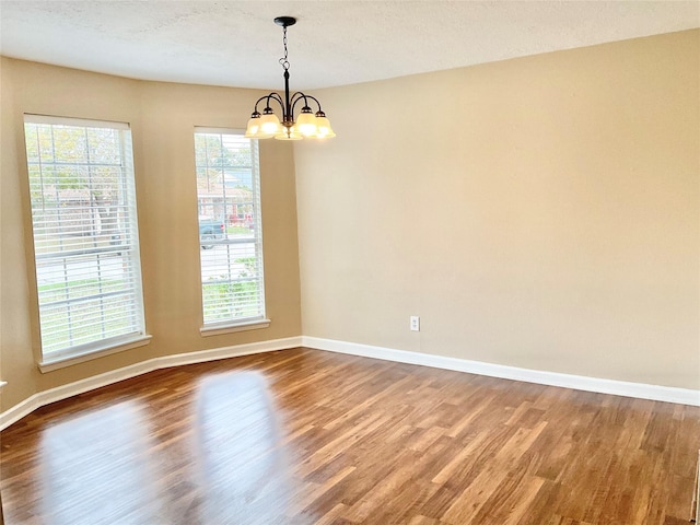 spare room with hardwood / wood-style floors, a chandelier, and a textured ceiling