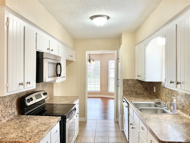 kitchen featuring a textured ceiling, stainless steel appliances, sink, light tile patterned floors, and white cabinets