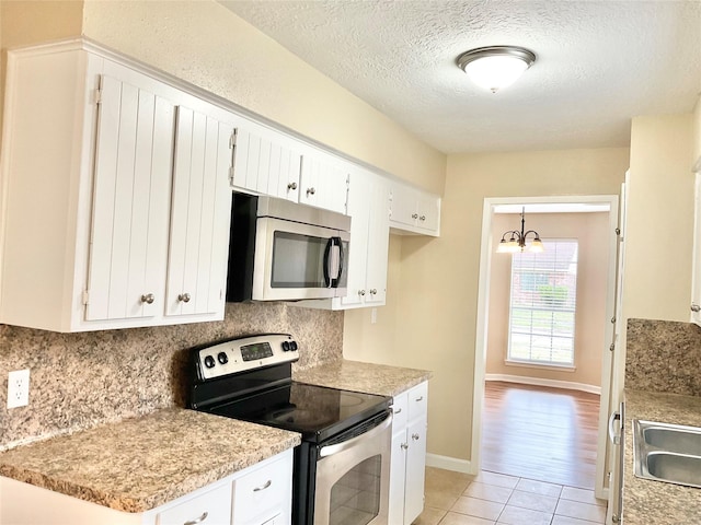 kitchen with hanging light fixtures, stainless steel appliances, a chandelier, light hardwood / wood-style floors, and white cabinets