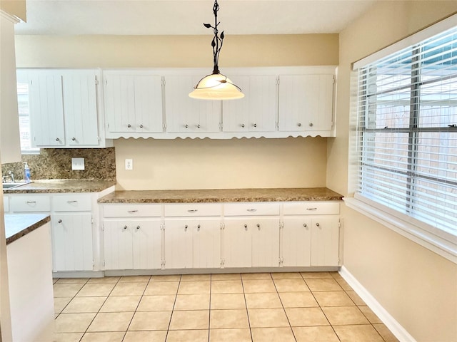 kitchen with pendant lighting, decorative backsplash, white cabinetry, and light tile patterned floors