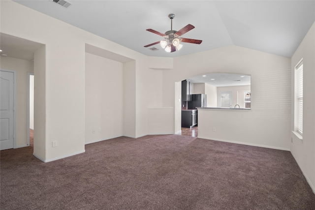 unfurnished living room with ceiling fan, dark carpet, and vaulted ceiling