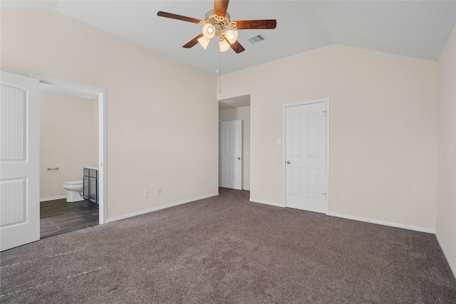 unfurnished bedroom featuring ceiling fan, ensuite bathroom, vaulted ceiling, a closet, and dark carpet