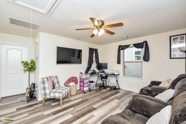 living room featuring a textured ceiling, light hardwood / wood-style flooring, and ceiling fan