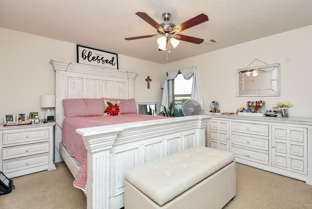 carpeted bedroom featuring ceiling fan and a textured ceiling