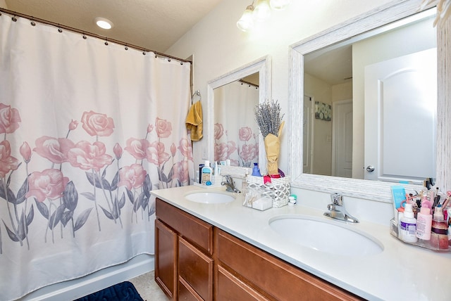 bathroom featuring a textured ceiling, vanity, and shower / bath combo with shower curtain