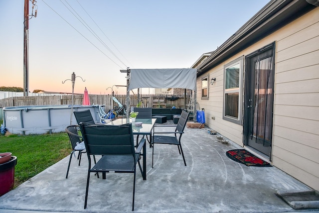 patio terrace at dusk with a fenced in pool