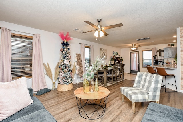 living room featuring a textured ceiling, light hardwood / wood-style flooring, a wealth of natural light, and ceiling fan