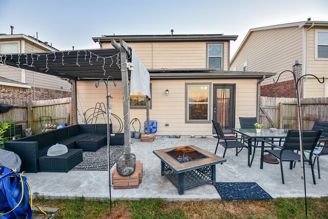 rear view of property featuring a patio area and an outdoor living space with a fire pit