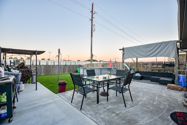 patio terrace at dusk with a lawn and an outdoor living space