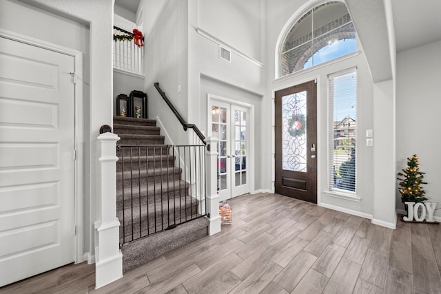 entryway featuring wood finished floors, visible vents, baseboards, french doors, and stairway