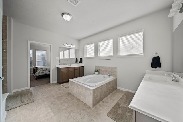 ensuite bathroom with plenty of natural light, two vanities, a sink, and visible vents