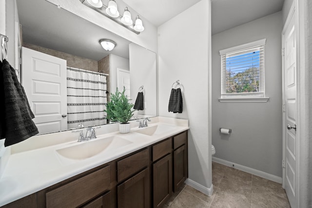 bathroom with baseboards, a sink, toilet, and double vanity