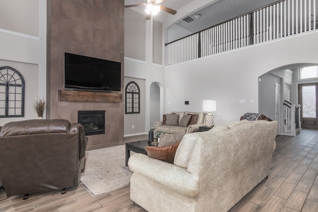 living room with wood tiled floor, a fireplace, arched walkways, and visible vents