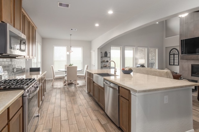 kitchen featuring visible vents, a sink, wood tiled floor, stainless steel appliances, and backsplash