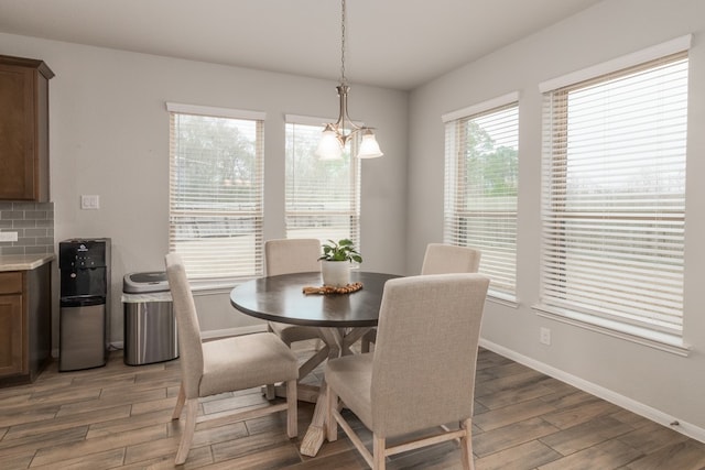 dining area with a chandelier, light wood finished floors, and baseboards